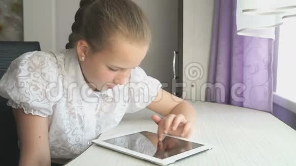 十几岁的女孩在桌子上用数码平板电脑视频的预览图