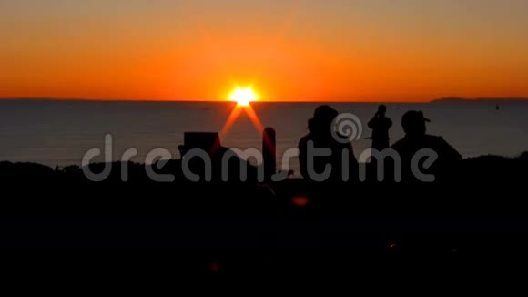在俯瞰海洋的长凳上抽雪茄骑自行车的人在日落时拍照高清1080视频的预览图
