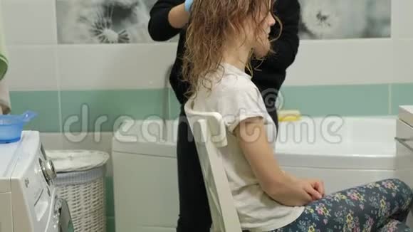 女理发师在家里的浴室里给一个年轻女人的头发涂上油漆用刷子涂上油漆视频的预览图