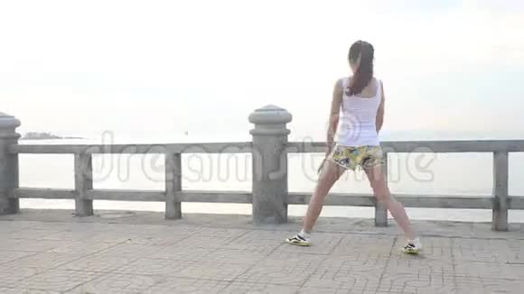 1亚洲女孩黎明时分在路堤上做运动视频的预览图