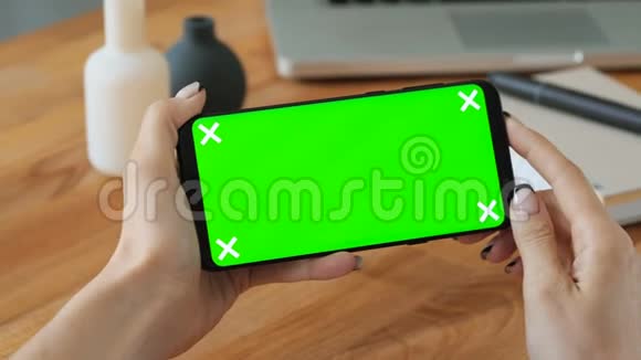 使用手机的人手拿绿色屏幕显示视频的预览图