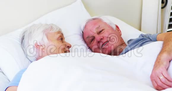 快乐的老两口在床上相互交流视频的预览图