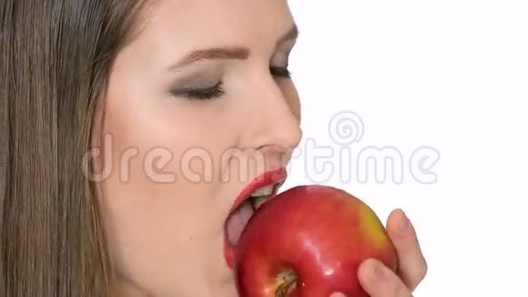 美丽的女孩在白色背景下吃红苹果视频的预览图