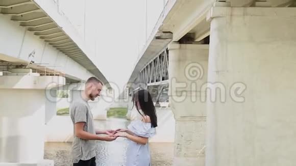 一对相爱的夫妇站在桥下拥抱和亲吻视频的预览图
