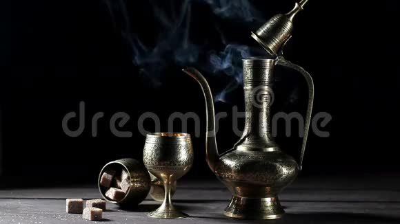 带摩洛哥茶的金属壶和杯子在黑烟场吸烟视频的预览图