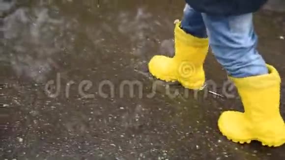 雨后小男孩走过春天的水坑视频的预览图