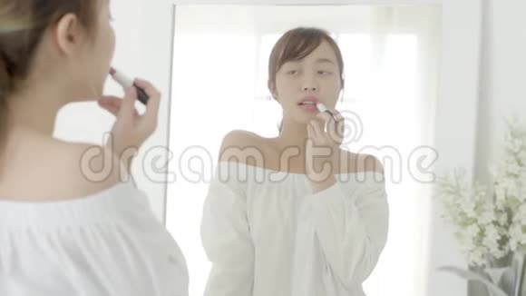美丽的肖像年轻的亚洲女人在镜子上涂抹和看化妆口红视频的预览图