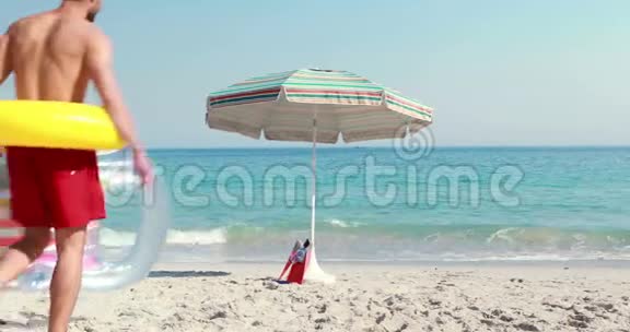 快乐的男人躺在沙滩上戴着橡胶圈视频的预览图
