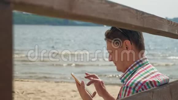 海滩上的一个男人用电脑平板电脑视频的预览图
