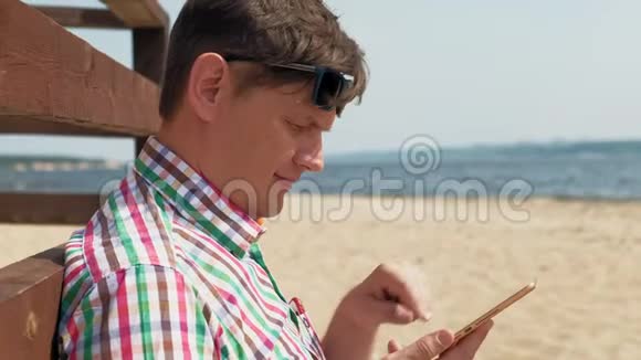 海滩上的一个男人用电脑平板电脑视频的预览图