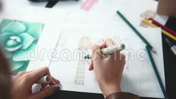 服装设计师用毛毡尖笔勾勒服装轮廓女性双手特写视频的预览图