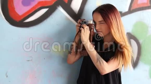 女孩用老式相机对着涂鸦墙和照片视频的预览图