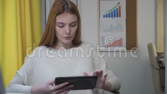 女人坐在工作场所手里拿着平板电脑视频的预览图