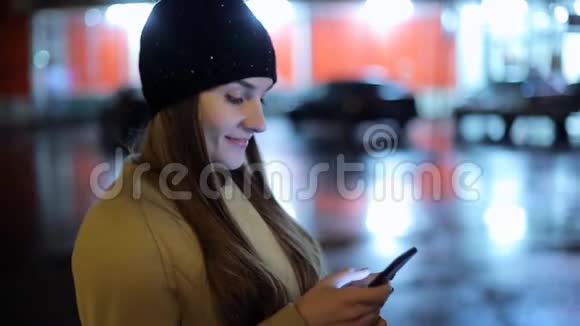 女孩手指屏幕智能手机的背景照明bokeh色光在夜间大气城市视频的预览图