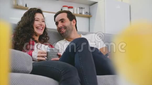 年轻夫妇在他们的公寓里放松躺在沙发上看电影视频的预览图