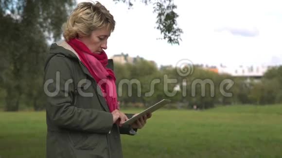公园里使用平板电脑的成年女性视频的预览图