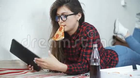 亚洲女人吃披萨在家看数码平板电脑视频的预览图