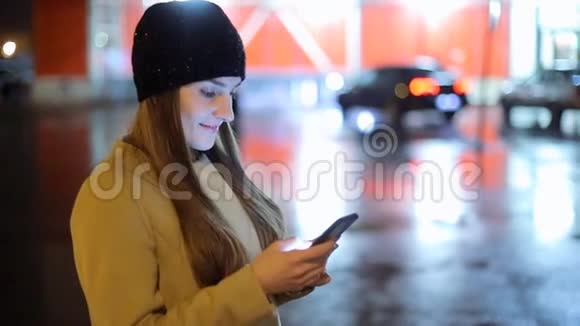 女孩手指屏幕智能手机的背景照明bokeh色光在夜间大气城市视频的预览图