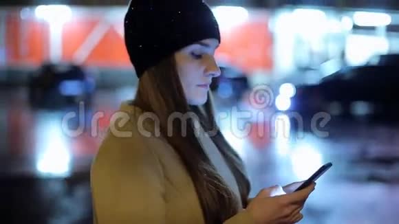 女孩指着屏幕智能手机在夜间大气中的背景照明波克色光视频的预览图