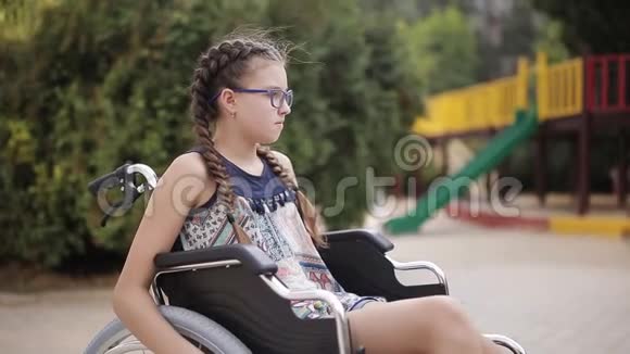 一个腿骨折的女孩坐在操场前的轮椅上视频的预览图