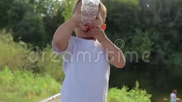 小男孩从自然界的一瓶水中喝水视频的预览图