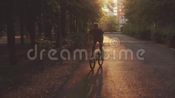 日落时在公园里骑自行车的年轻人视频的预览图