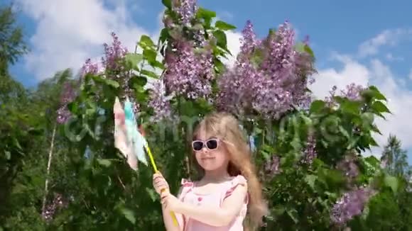 一个小女孩在一个公园里旁边是春天盛开的紫丁香视频的预览图