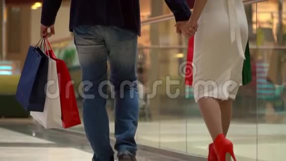 那个男人和那个女人一起买圣诞礼物购物中心的买家手里拿着大的多色包裹夫妇视频的预览图