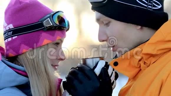 恋爱中的夫妻在背光的阳光下享受一杯饮料男人和女人在冬天的森林里喝茶喝咖啡视频的预览图
