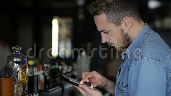 一个男人坐在酒吧里用平板电脑视频的预览图
