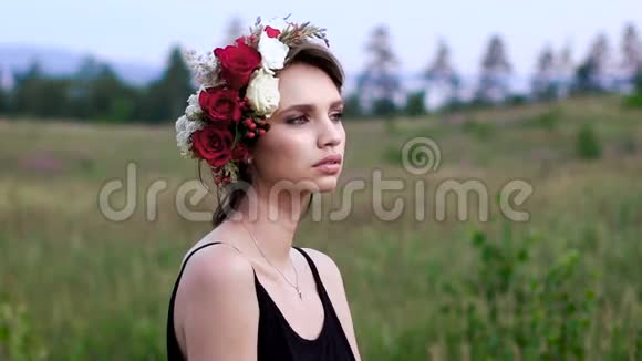 美丽的女孩穿着黑色短裙头上戴着花环在绿色的田野上视频的预览图