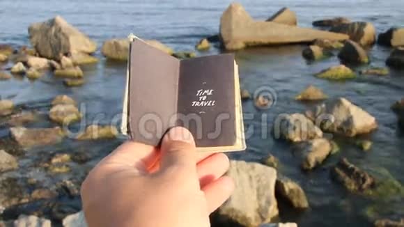 旅行的时间到了手拿着一本书上面写着大海上的铭文和岩石视频的预览图