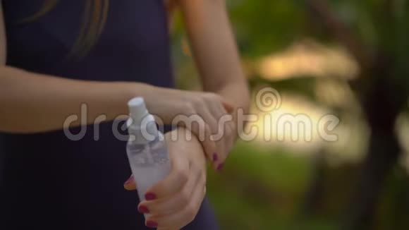 一位美丽的年轻女子用防蚊剂喷在皮肤上的超慢镜头一片热带视频的预览图