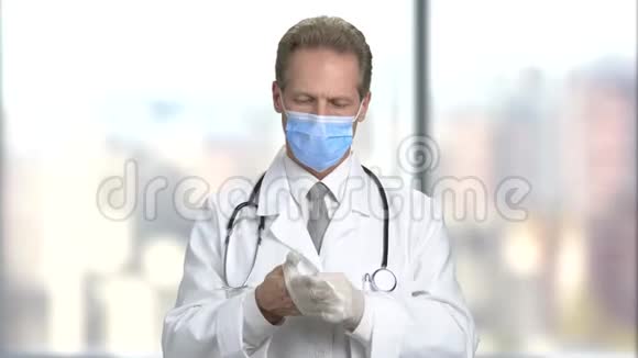 戴口罩的严肃医生戴上手套视频的预览图