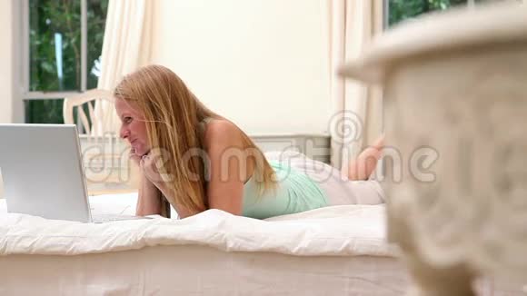 女人躺在床上用笔记本电脑上的视频聊天视频的预览图