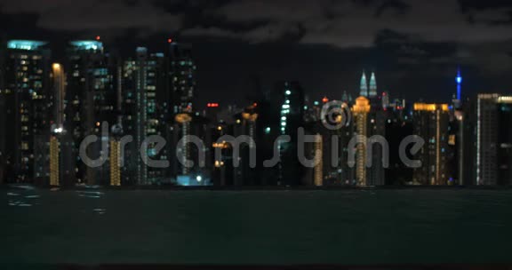 在摩天大楼屋顶上的游泳池里游泳的女性景观与夜晚的城市景观马来西亚吉隆坡视频的预览图