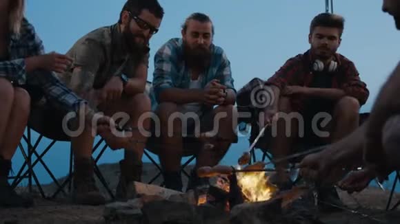 朋友在黄昏的篝火上煎香肠视频的预览图