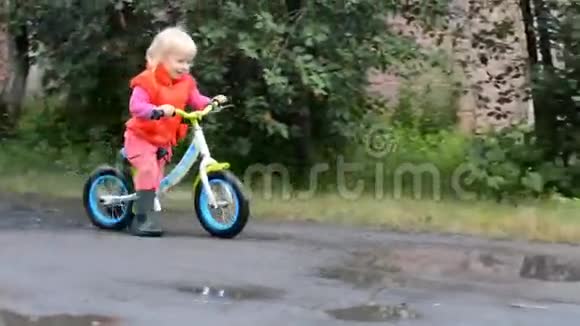 在湿漉漉的大街上骑自行车的小女孩视频的预览图