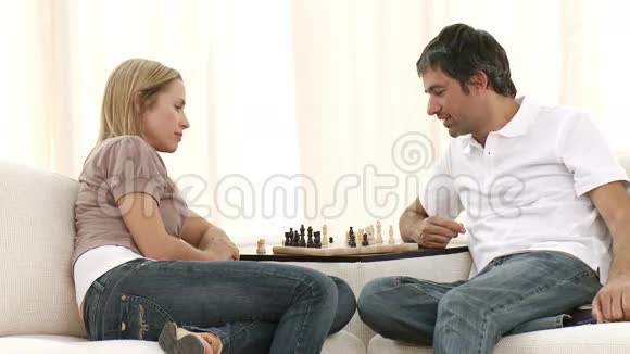 女人和男人在客厅的沙发上下棋视频的预览图