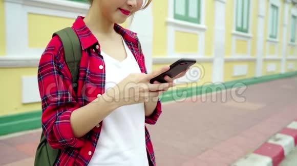 亚洲女游客背包客微笑使用智能手机独自旅行在曼谷的城市街道户外度假泰国视频的预览图