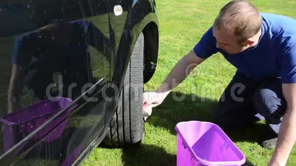 年轻人用肥皂清洗他最喜欢的汽车车轮视频的预览图