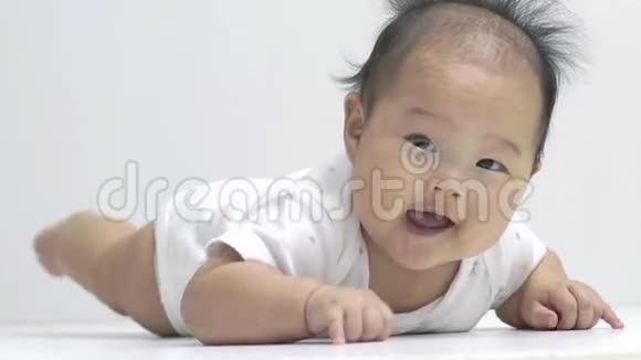 可爱的亚洲中国宝宝在肚子上缓慢地滚动视频的预览图