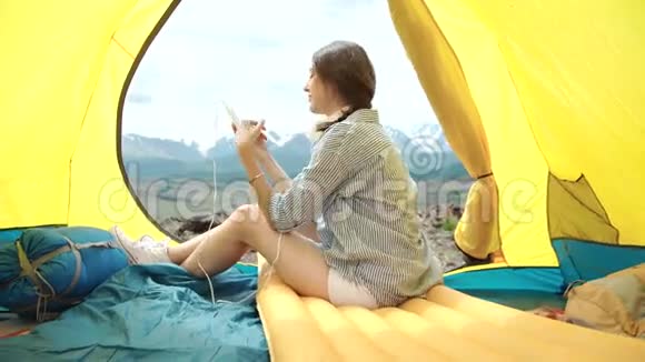 一个女人在帐篷和睡袋里打电话视频的预览图