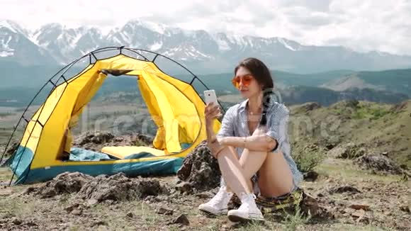 一个女人在帐篷和睡袋里打电话视频的预览图