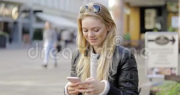 微笑的女人在街上使用智能手机视频的预览图
