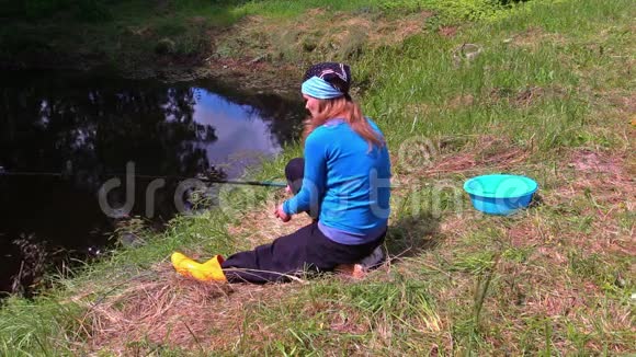 怀孕的女孩坐在湖岸和可爱的猫捕鱼视频的预览图