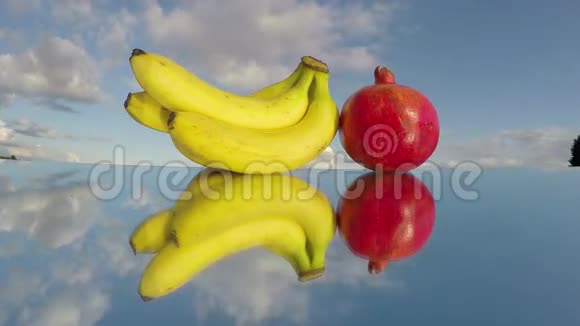 香蕉和石榴果实在镜子和云彩上运动延时4K视频的预览图