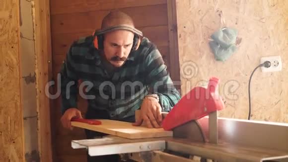 大胆用小胡子木工人用电动夹具锯切木板视频的预览图