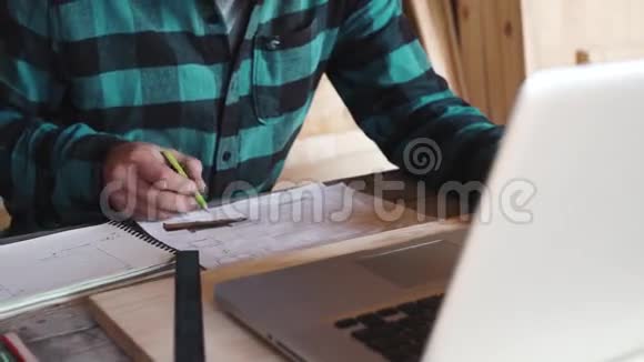 木匠在他的车间里用绘图设备纸尺子铅笔和笔记本电脑工作视频的预览图