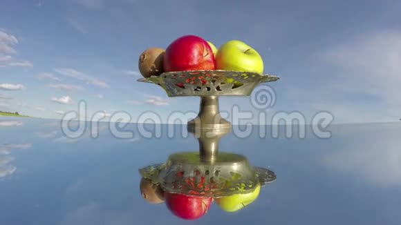 老式花瓶镜子上的水果在空间和天空云延时4K视频的预览图